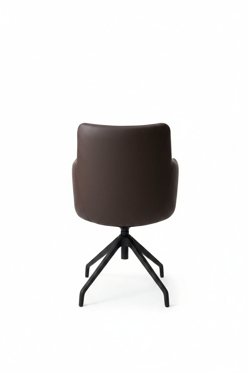 Black chair on a concrete floor with a gray wall in the background