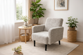 Gray armchair in a living room with a plant and decor items.