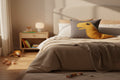 Gray pillow with a yellow dinosaur design on a brown surface against a light gray background